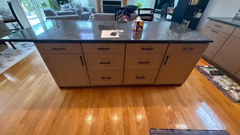 Refaced island with a dark granite top over hardwood in the open-plan kitchen