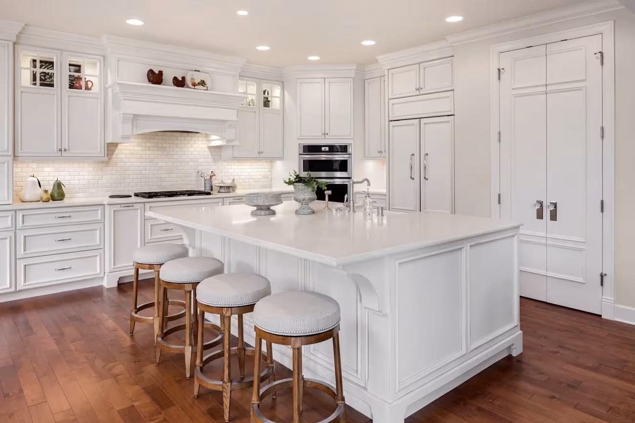 White kitchen with a large island and counter stools in an Elgin home