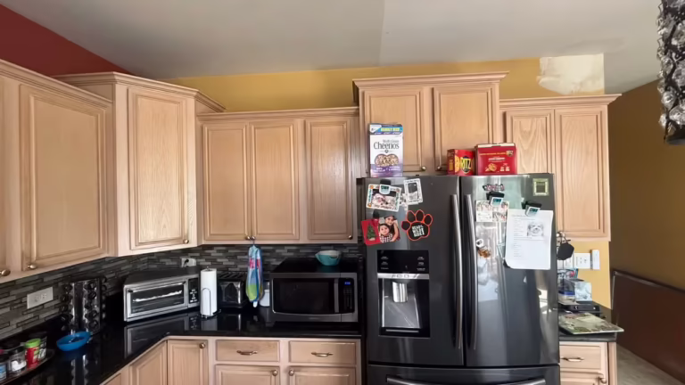 Maple uppers beside the black refrigerator in the kitchen awaiting refacing
