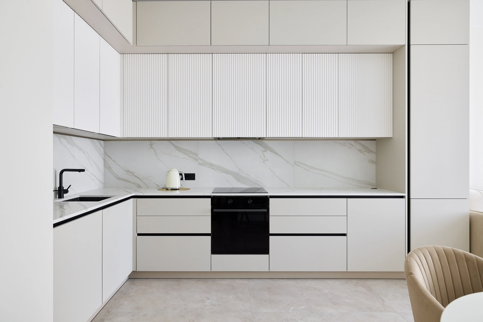White handleless cabinets and a marble backsplash in a modern kitchen