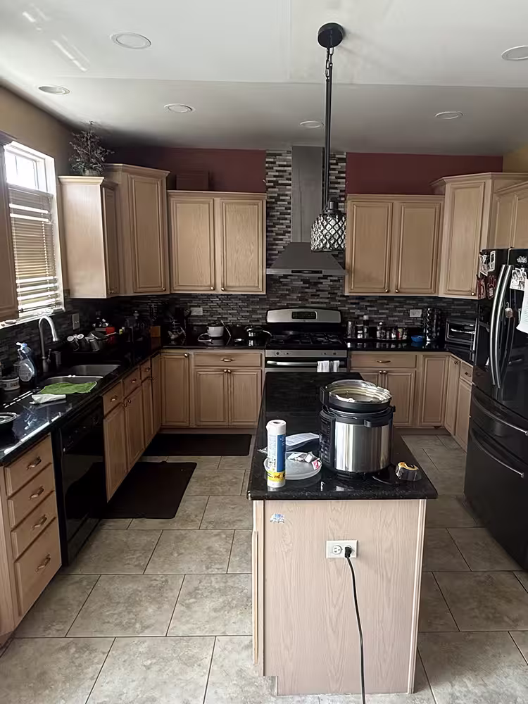 Light maple cabinets with black countertops and black appliances before the sage gray change
