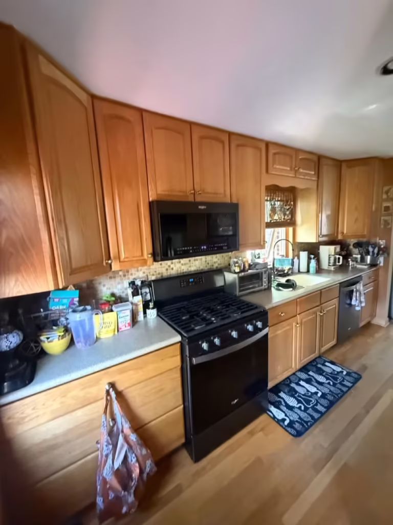 Honey oak uppers and countertops in the orange-walled kitchen before refacing
