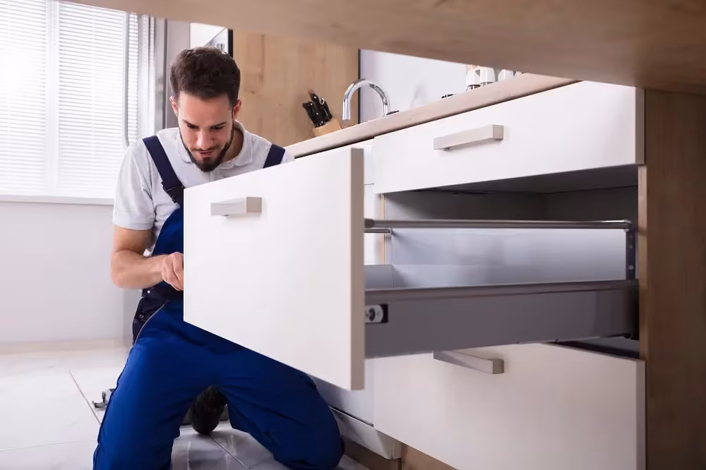 Installer fitting a white drawer front to a base cabinet