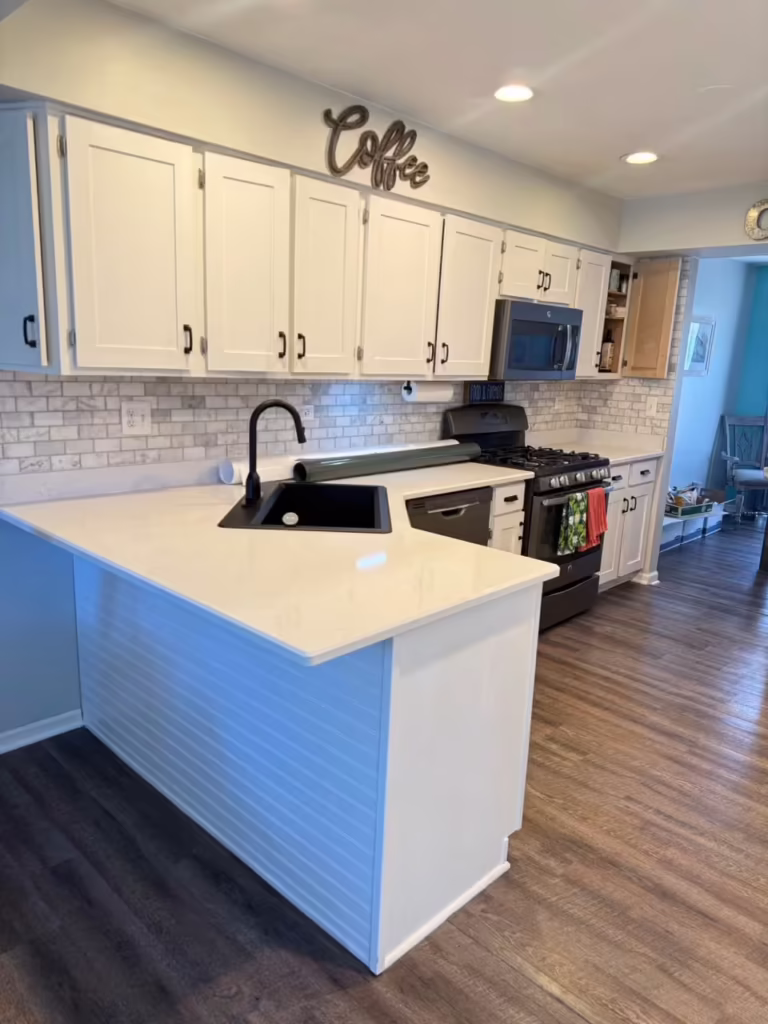 All-white peninsula and cabinets after refacing the two-tone teal kitchen