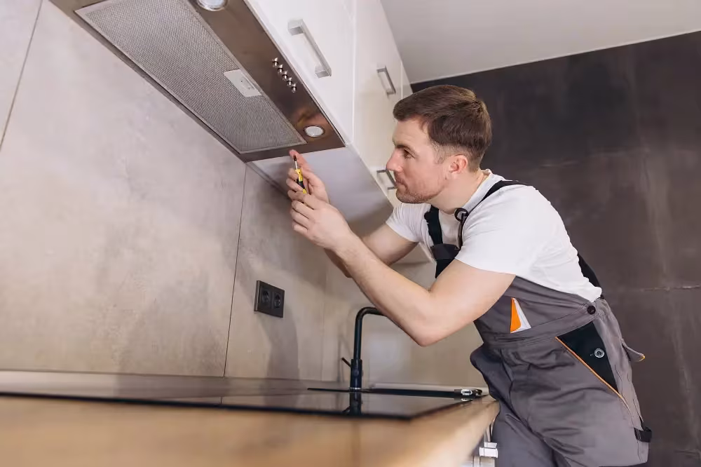 Technician installing an extractor hood above a hob