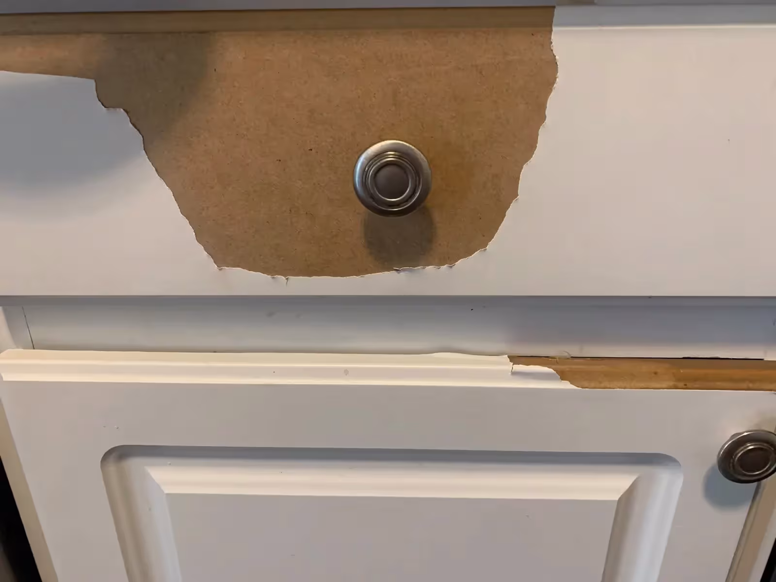 Thermofoil laminate peeling away from a cabinet door around the knob