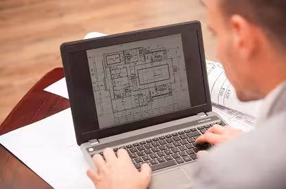 Designer drafting a CAD wall panel layout on a laptop