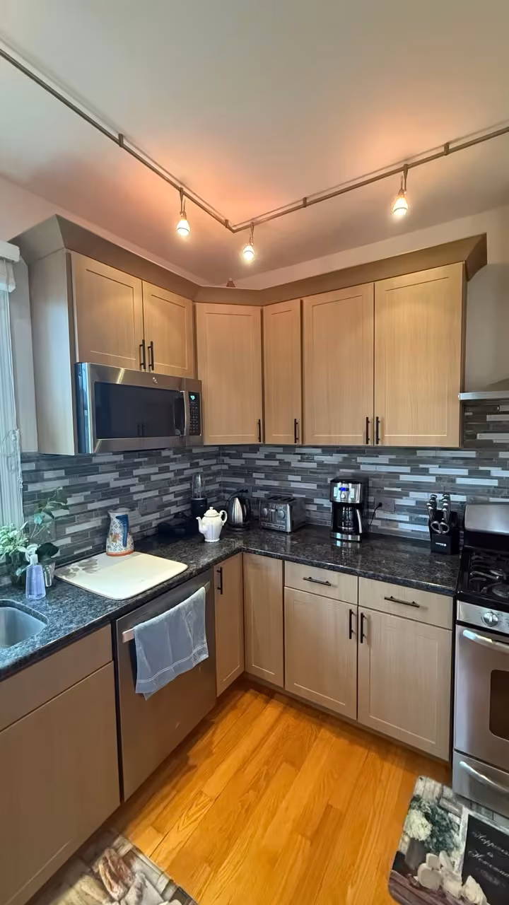 Pale refaced cabinets beside the blue mosaic backsplash after the project