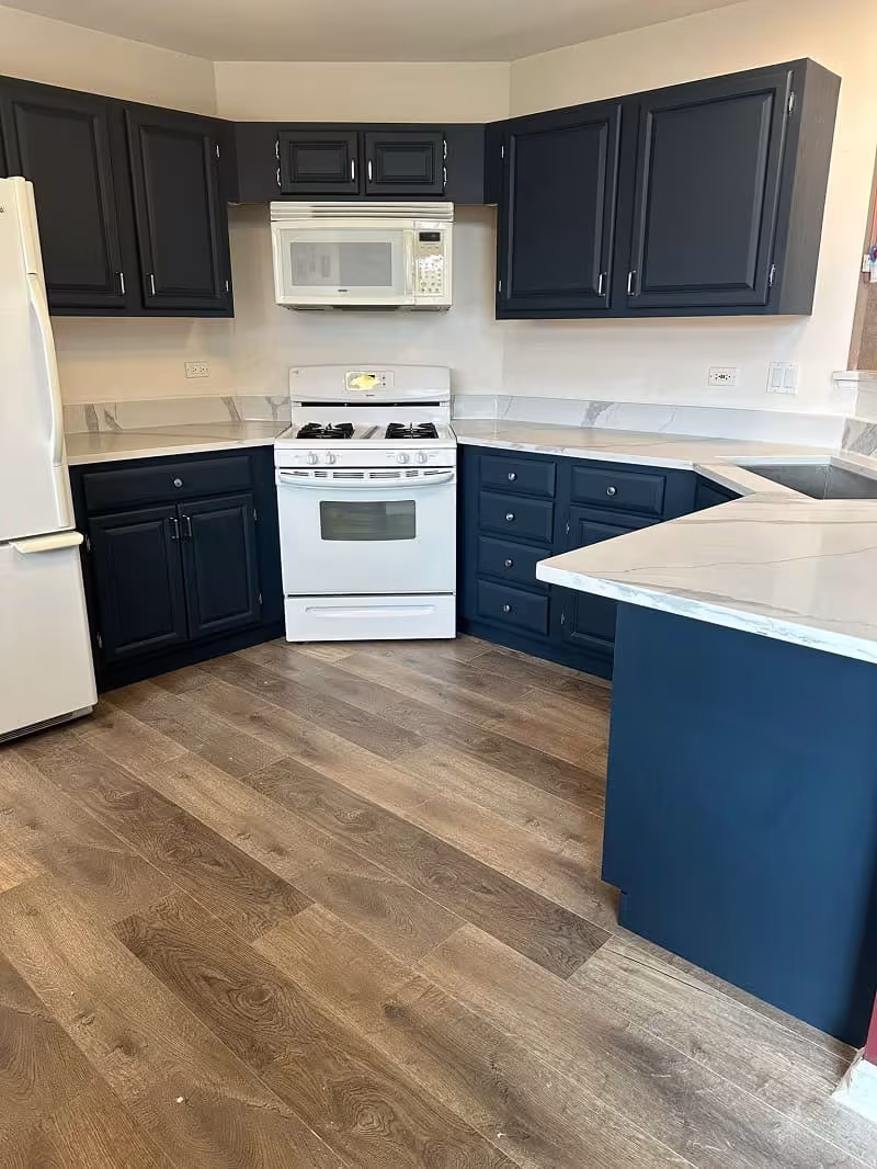 Navy blue base cabinets under white uppers after the Bartlett refacing