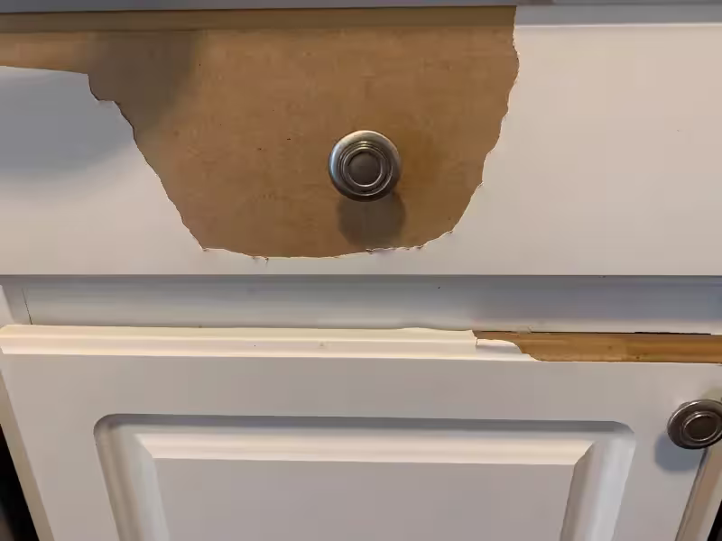 Thermofoil coating lifting away from a white cabinet door