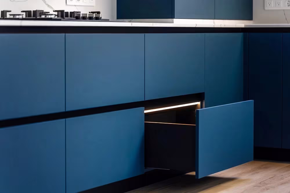 Deep blue handleless cabinets with a drawer pulled open