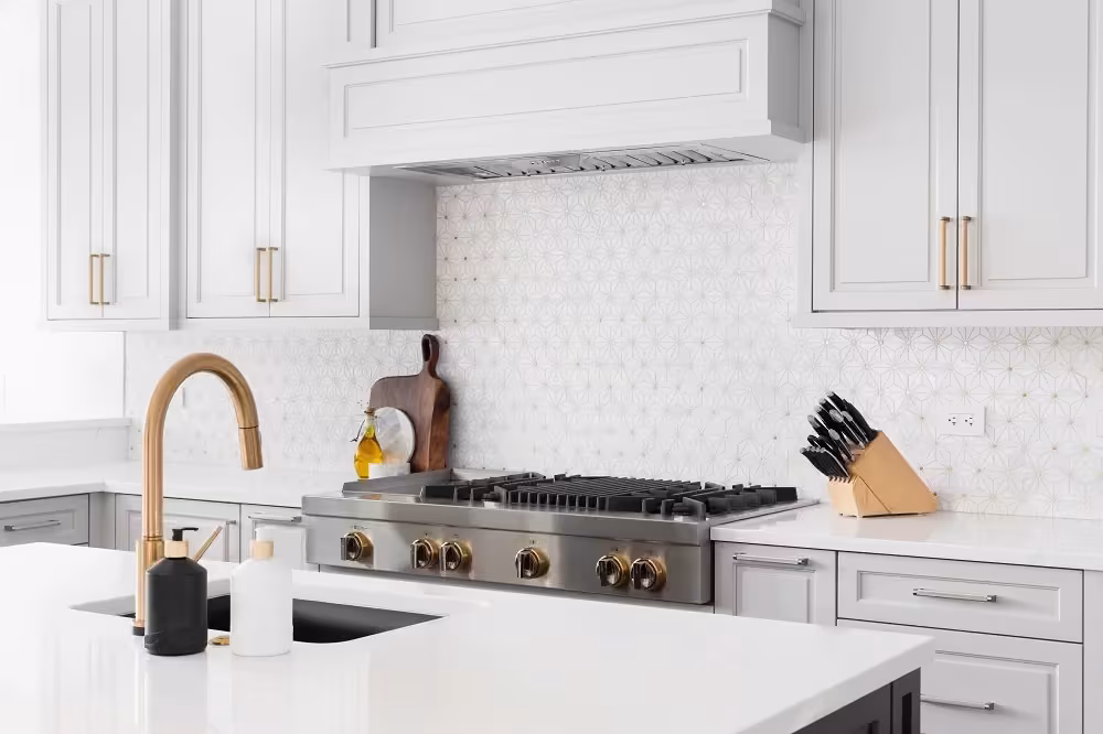 White kitchen with brass bar pulls and a copper faucet