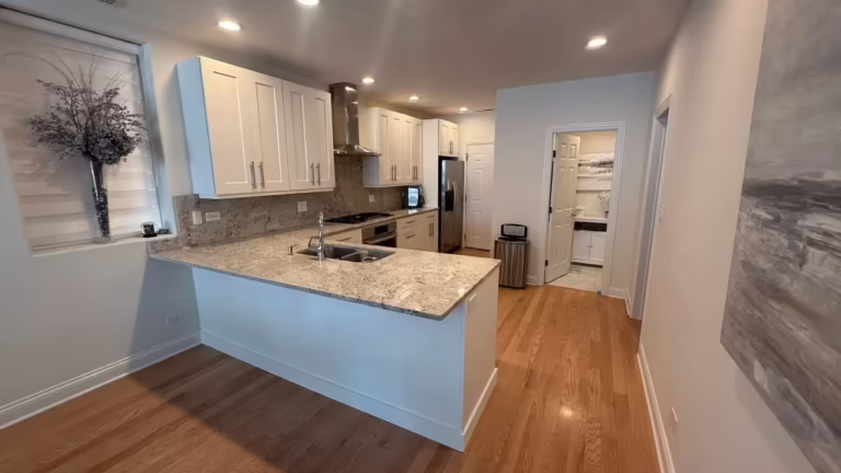 White refaced cabinets and a marble peninsula opening up the espresso kitchen