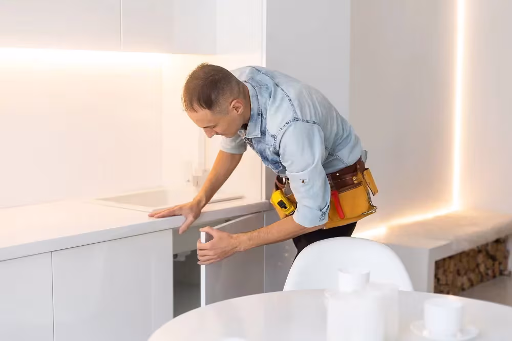 Installer fitting a white base cabinet panel during a replacement