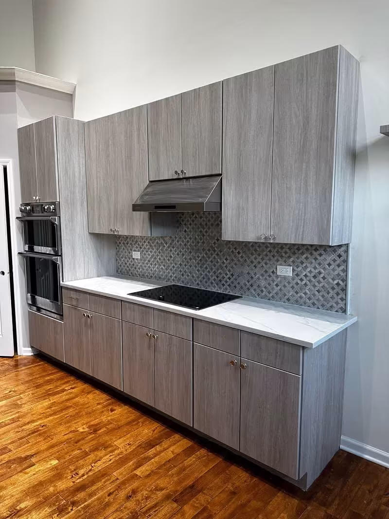Gray woodgrain 3D laminate cabinets and mosaic backsplash in the Northbrook kitchen