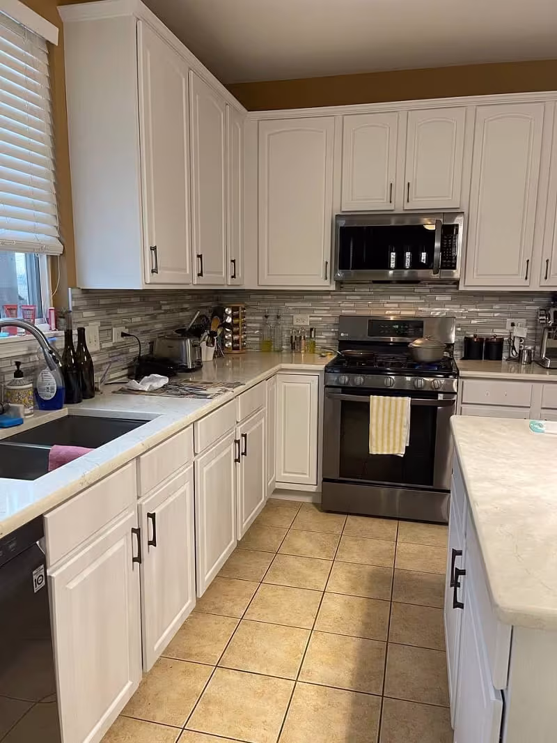 White refaced cabinets above the tile backsplash in the finished kitchen