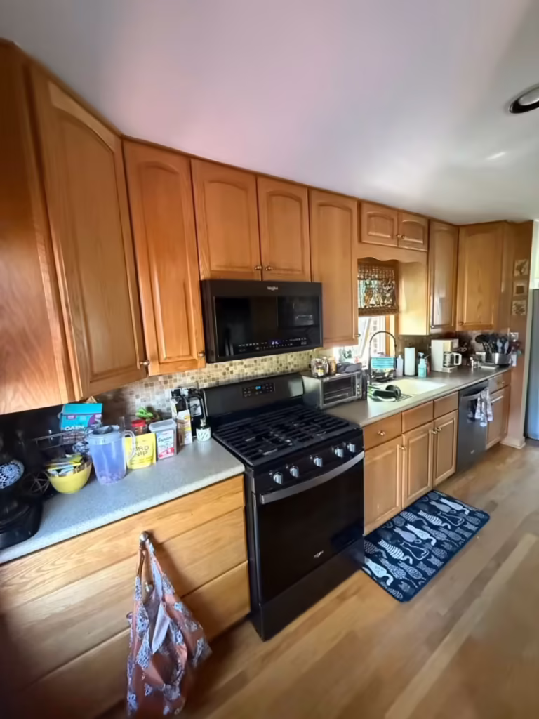 Oak cabinets and a black range against orange accent walls before refacing