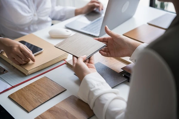 Hands comparing wood and stone samples across a meeting table