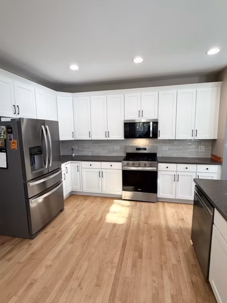White refaced cabinets and gray countertops in the finished kitchen