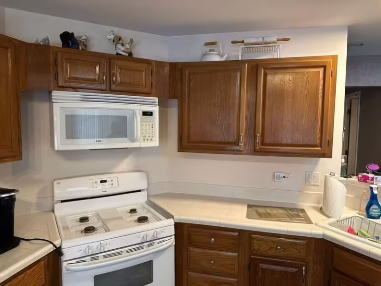 Outdated oak cabinets and white appliances in a Bartlett kitchen before budget refacing