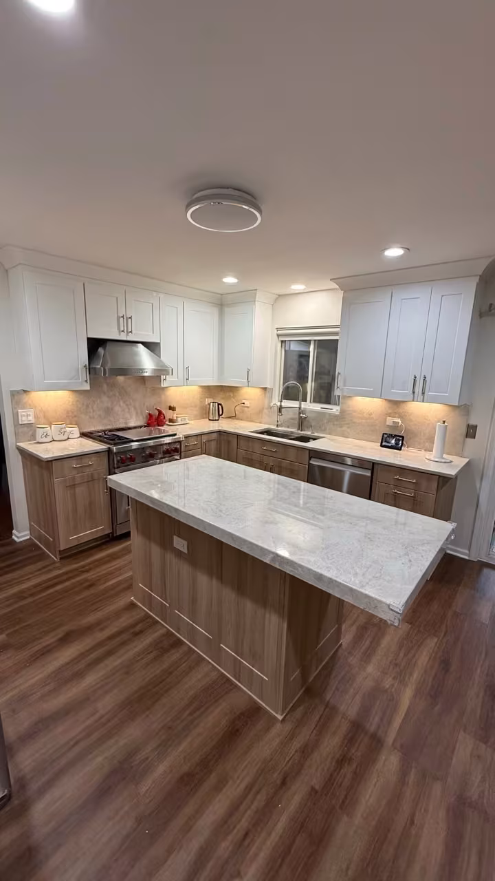 Custom wood island with a marble top at the center of the refaced kitchen