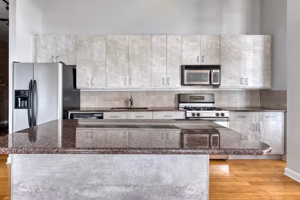Marble-look cabinet fronts and a dark stone island in a modern Chicagoland kitchen