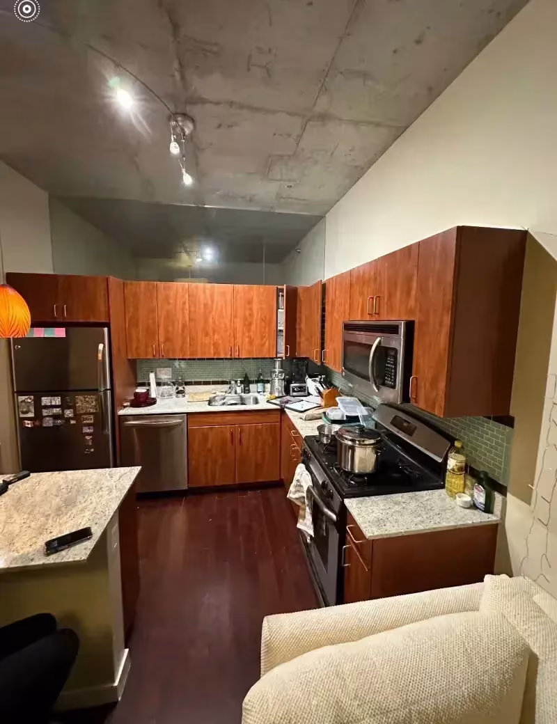 Dark cherry loft kitchen under a concrete ceiling in downtown Chicago before repair