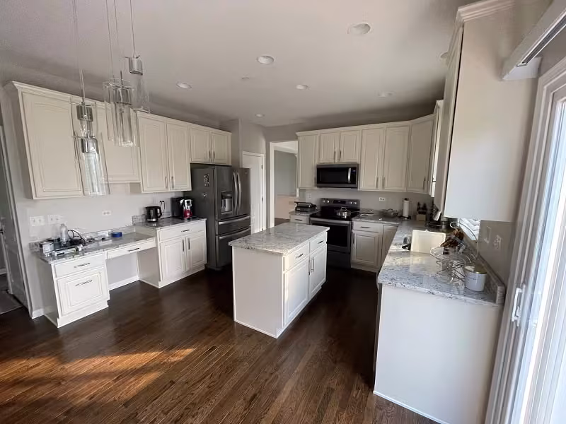 White refaced cabinets and island in the brightened Chicagoland kitchen
