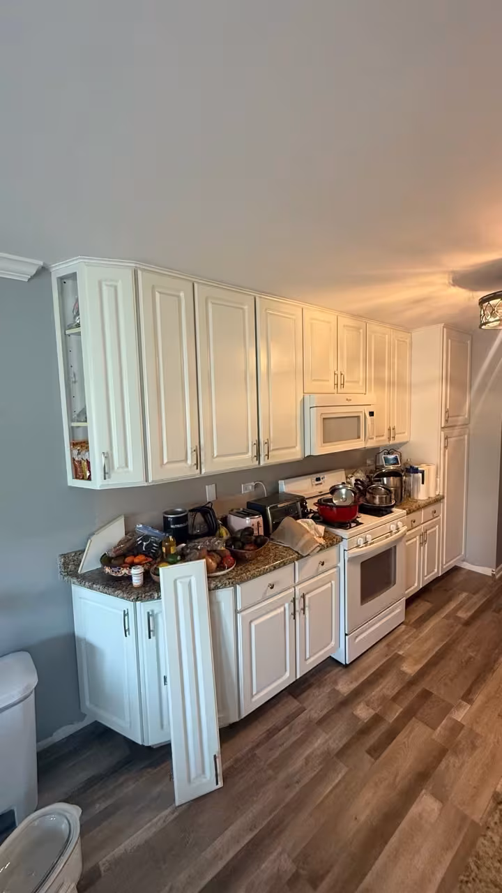 White galley cabinets and hardwood flooring before the navy refacing