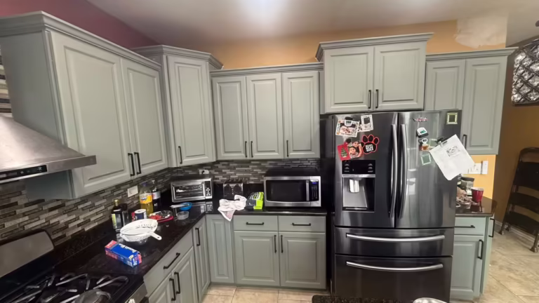 Sage gray uppers beside the black stainless refrigerator after the refacing project