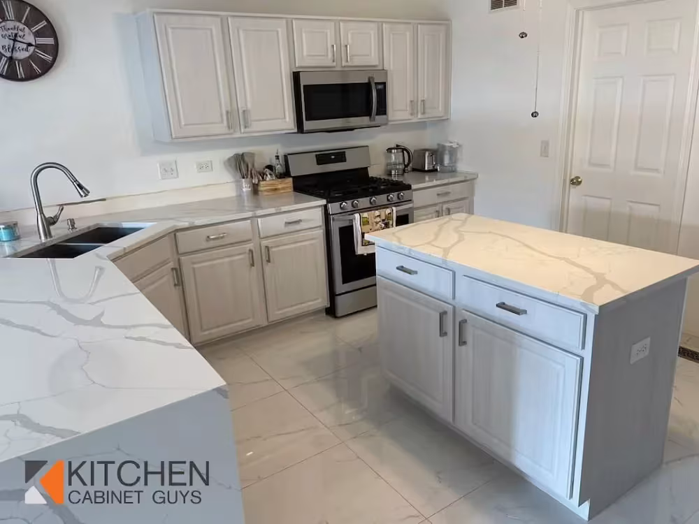 White kitchen with a gray island and quartz counters after refacing