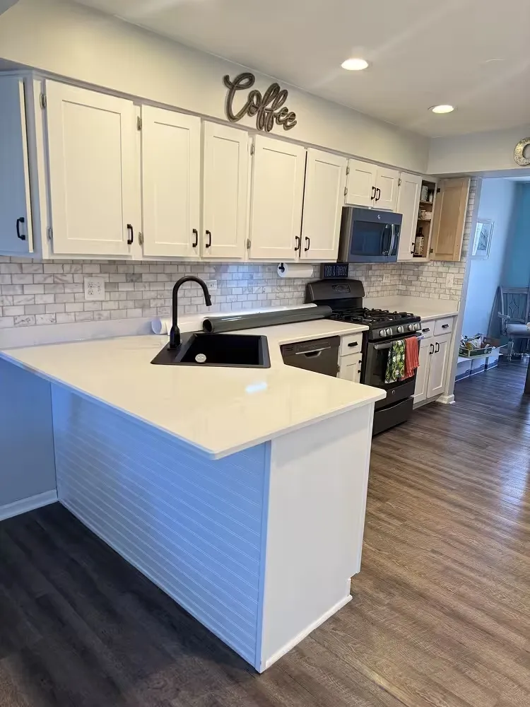 Kitchen after refacing, with white shaker cabinets and a white peninsula