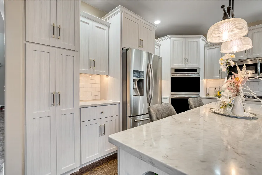 White shaker kitchen cabinets with marble counters and stainless appliances
