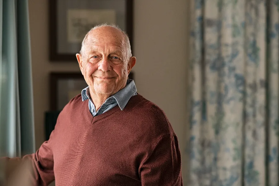 Smiling senior man in a red sweater at home